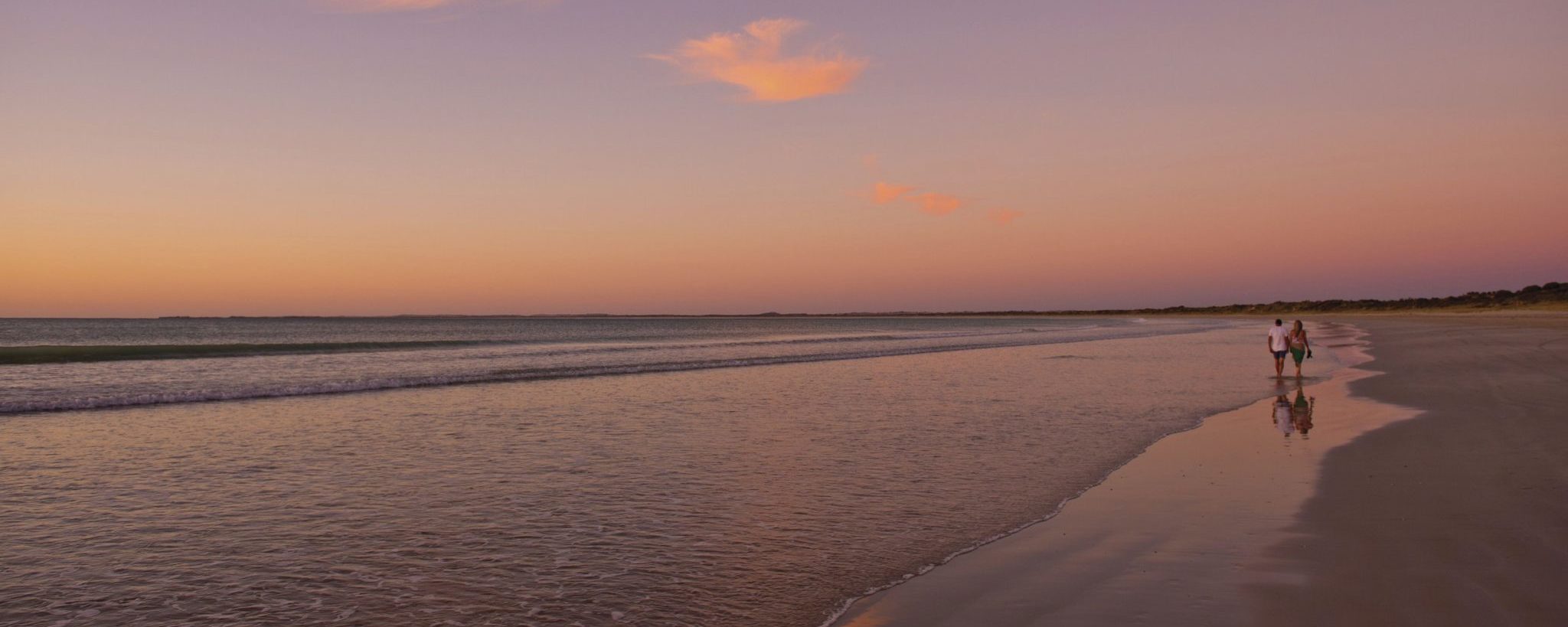 Two people walking along Long Beach.