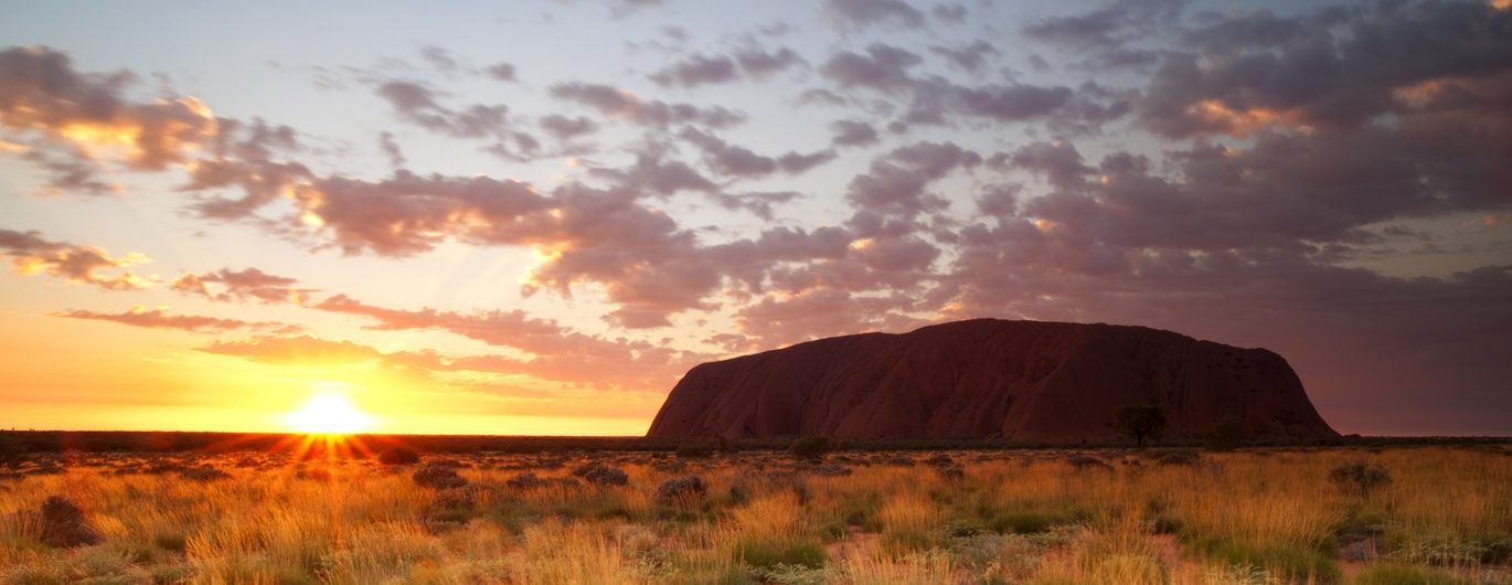 Sun sets in the distance near Uluru, Northern Territory.