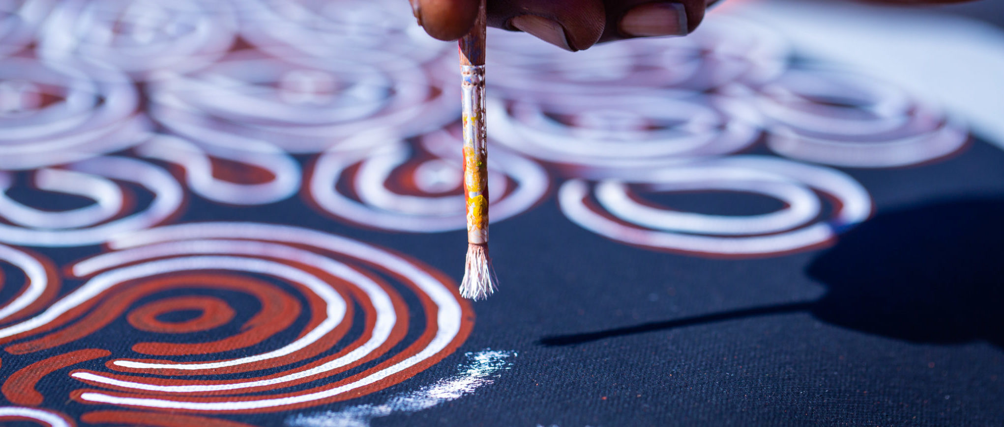 An Aboriginal artist working on a painting. The Maruku Arts gallery is located at the cultural centre in Uluru-Kata Tjuta National Park. We offer an overall understanding of local Aboriginal culture through quality art & craft. It is the perfect opportunity to meet, understand the culture and purchase works from local artists, knowing that all funds are returned to the Anangu people.