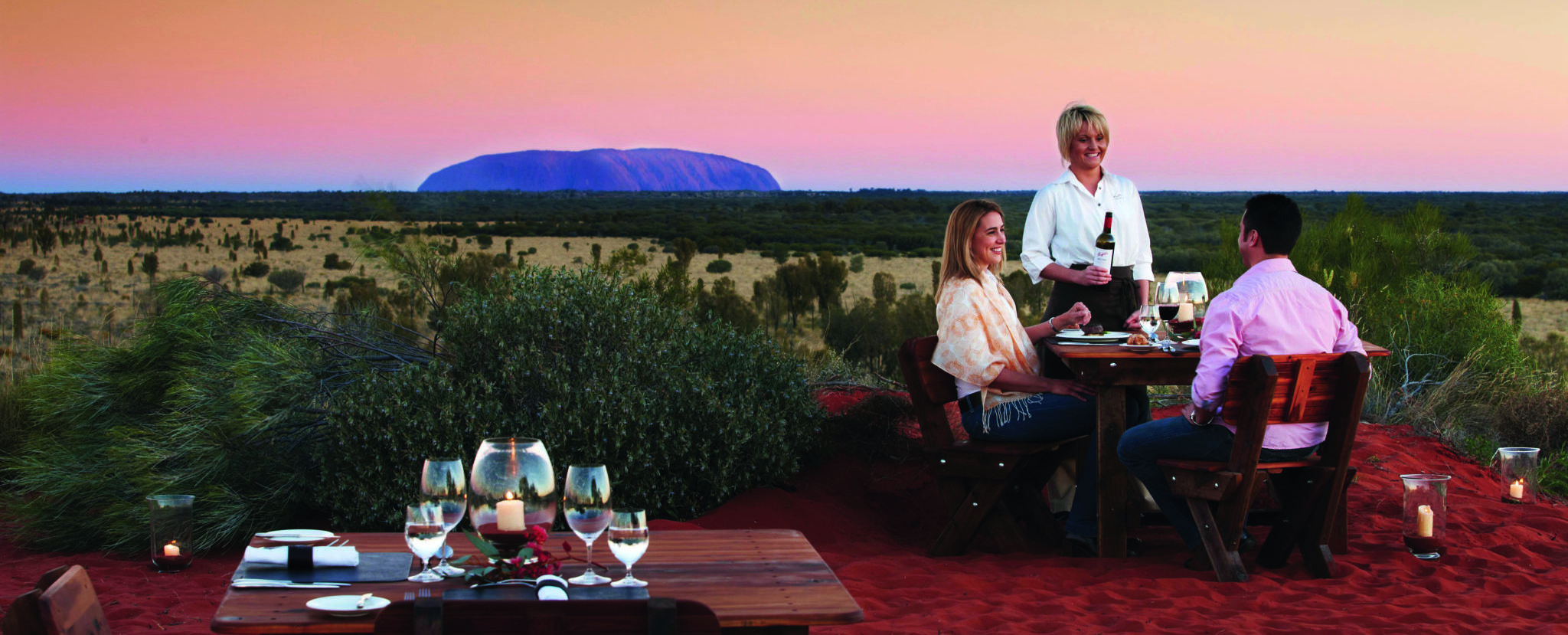 A couple dining at Tali Wiru as the sunsets over Uluru.