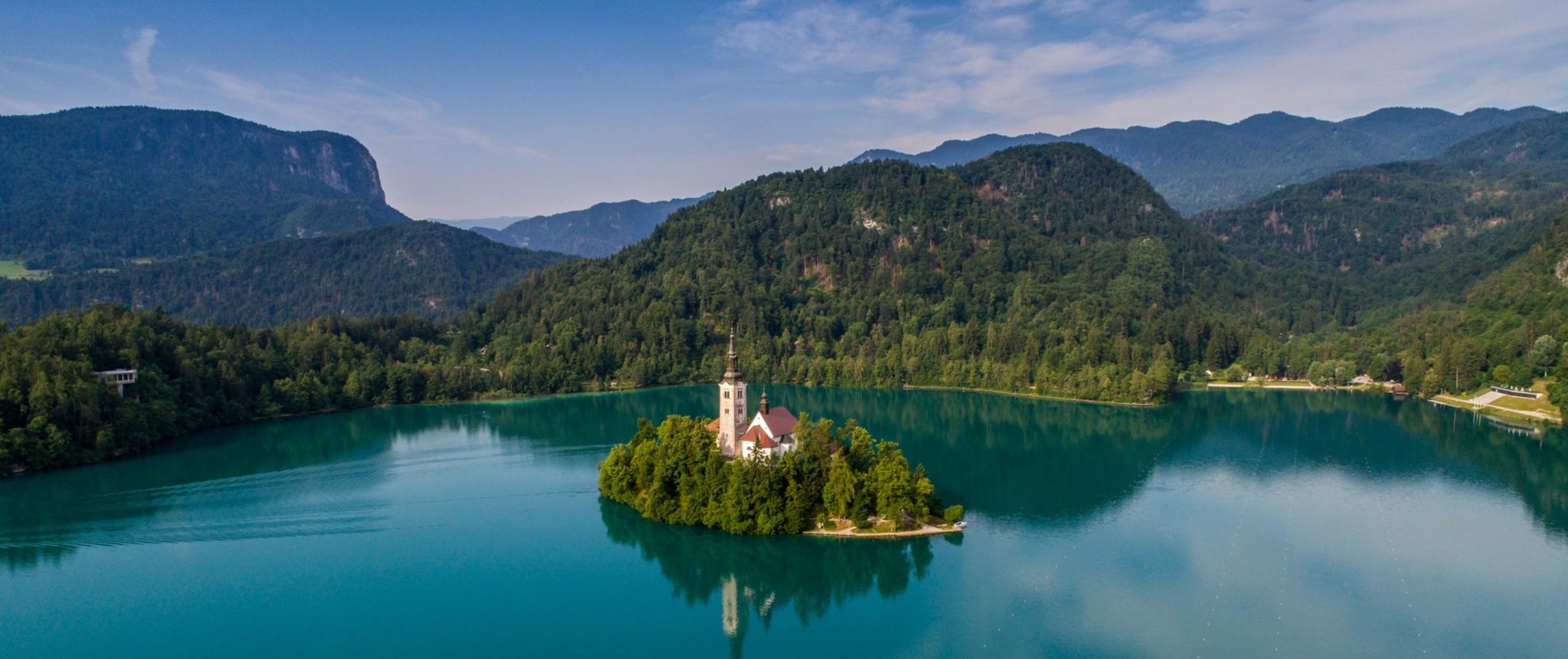 Turquoise-coloured lake in Slovenia with a church on an island in the middle of the water.